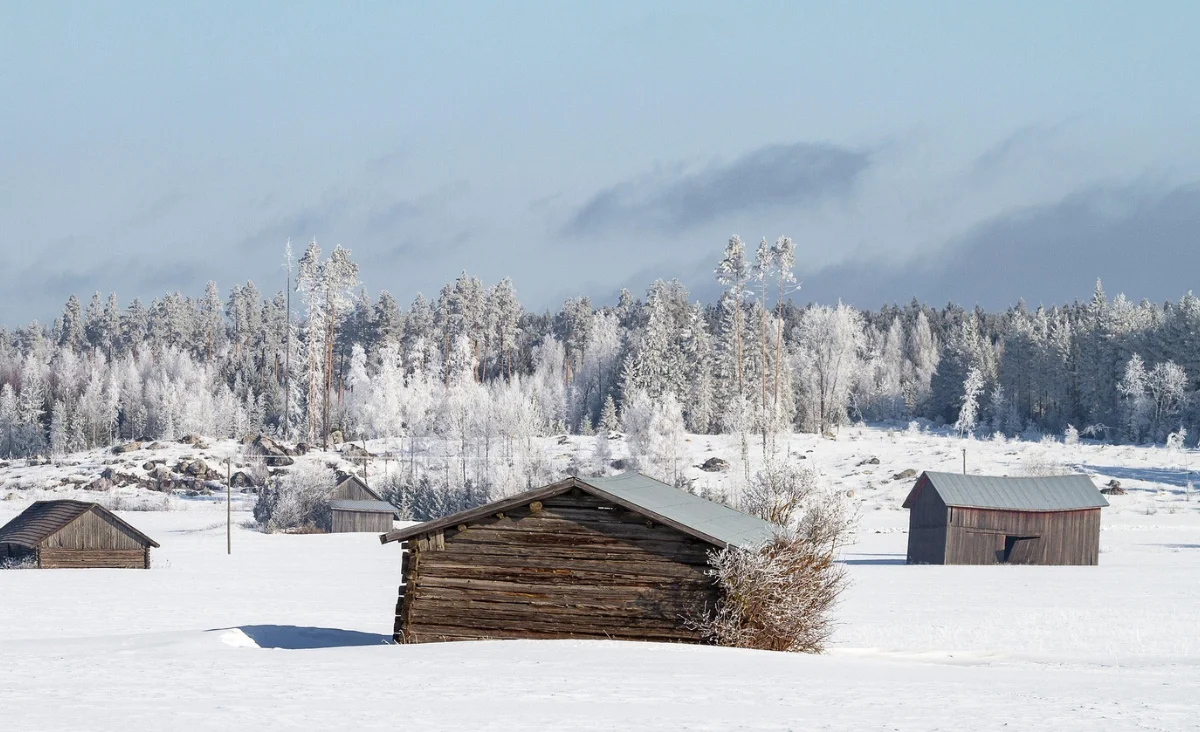 Eine winterliche Szene mit einem schneebedeckten Feld und einigen Gebäuden in Finnland.