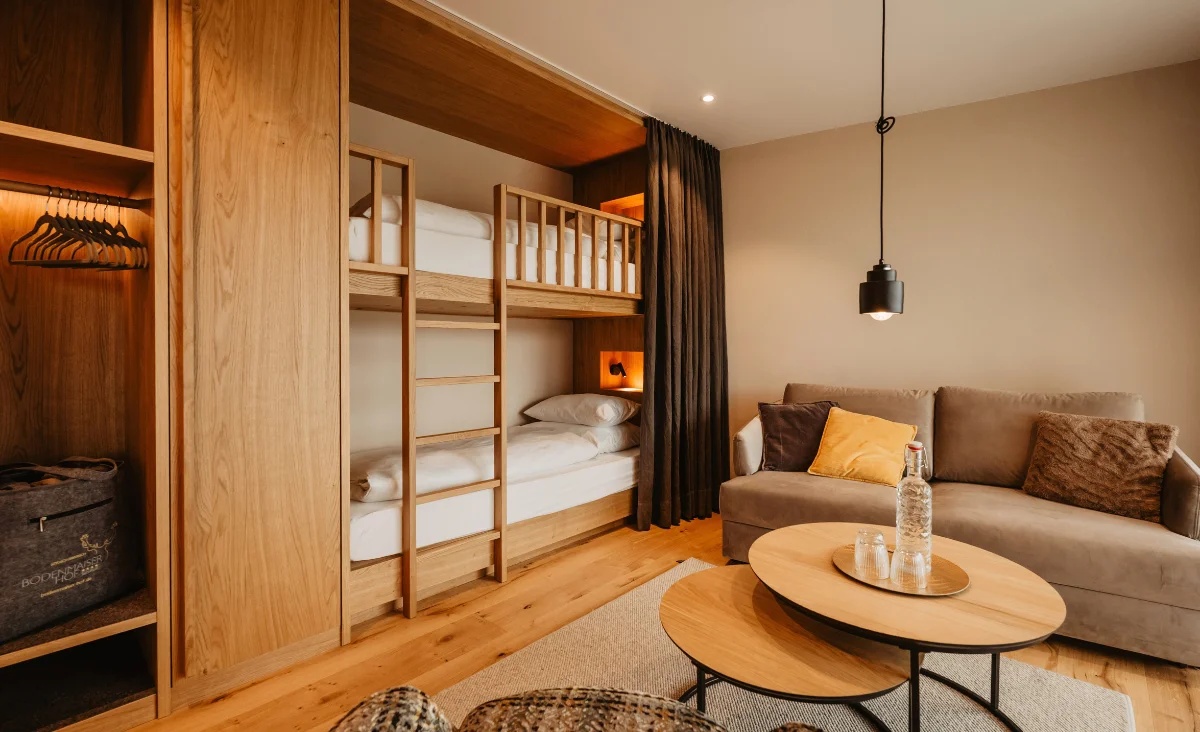 Modernes Familienzimmer im Hotel Bodenmaiser Hof mit Holz-Etagenbett, gemütlichem Sofa und stilvollen Holzmöbeln