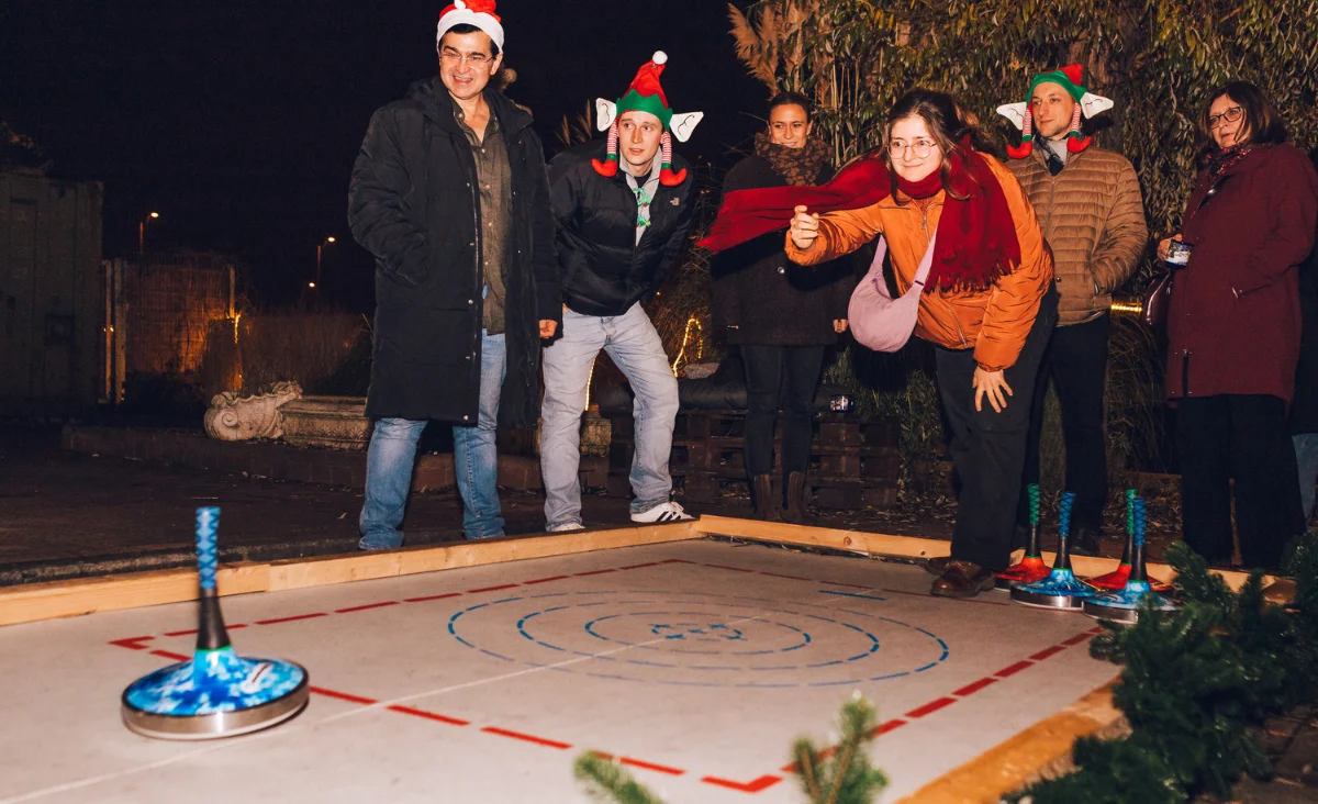 Gäste beim winterlichen Eisstockschießen im Außenbereich während des All Inclusive Weihnachtsmarkt Schöneweide