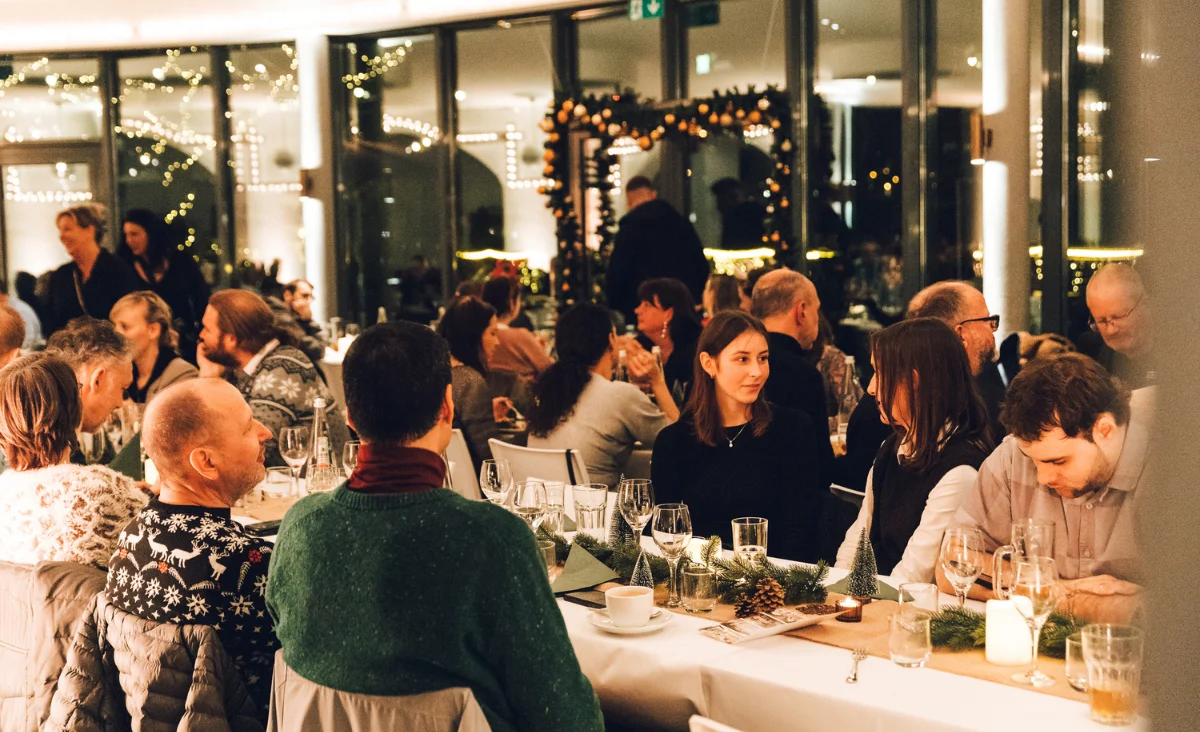 Gäste beim gemütlichen Beisammensein und festlichen Dinner im stimmungsvoll beleuchteten Raum beim All Inclusive Weihnachtsmarkt Schöneweide
