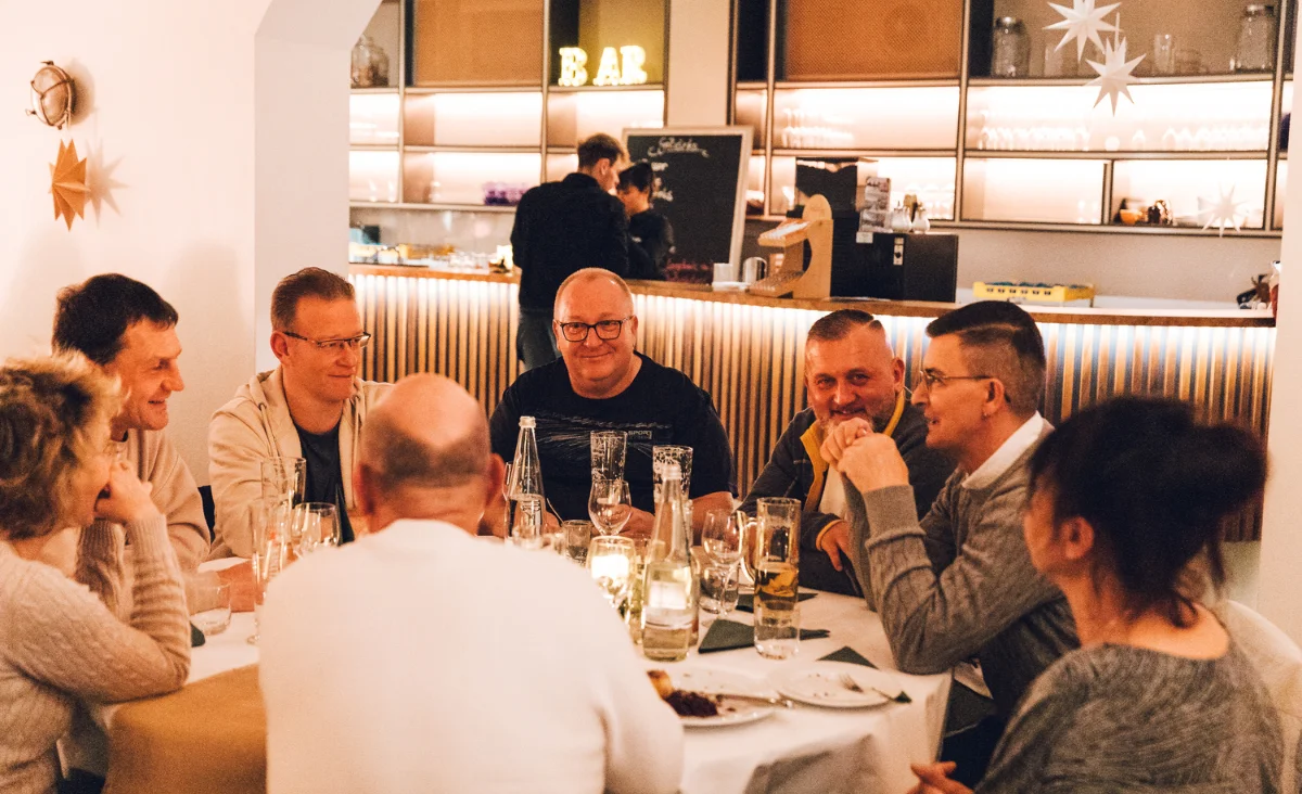 Gäste beim gemütlichen Beisammensein und Abendessen an Tischen vor der Bar beim All Inclusive Weihnachtsmarkt Schöneweide