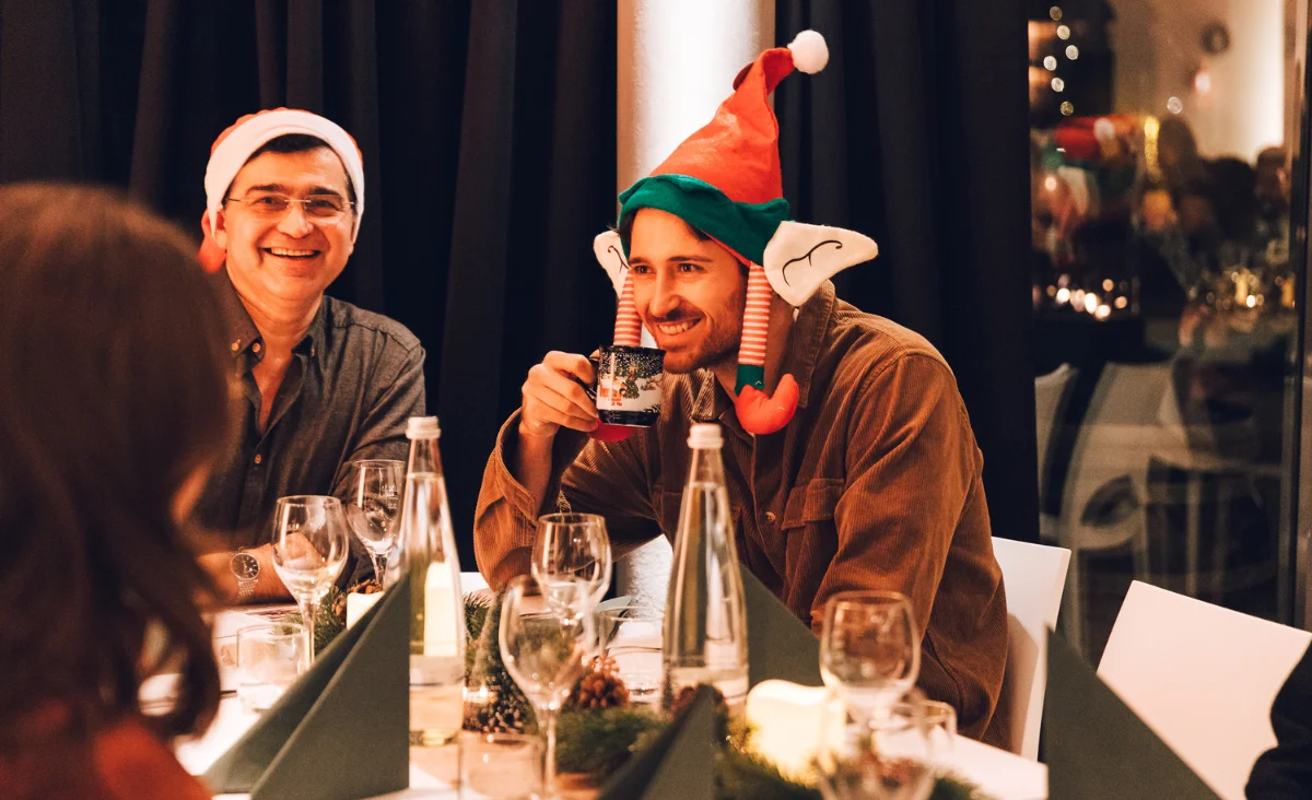 Gut gelaunte Gäste beim All Inclusive Weihnachtsmarkt Schöneweide mit Weihnachtsmütze und Glühwein in festlicher Atmosphäre