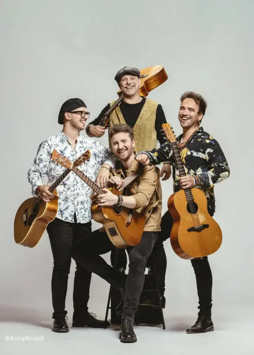Die Band posiert mit ihren Gitarren für ein Gruppenfoto, lächelnd und in lässiger Kleidung von der Gitarrensensation 40 Fingers.